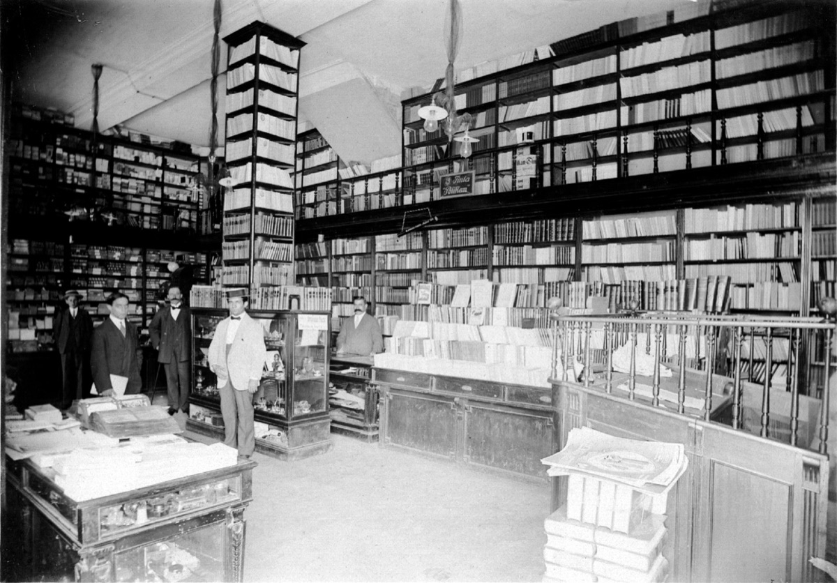 Interior de la librería La Normal a comienzos del siglo XX, con altas estanterías de madera y empleados de época.